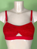 A red soft cup bra with a textured lace-like fabric and adjustable shoulder straps, displayed on a white mannequin torso against a solid light green background.