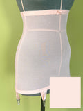 A peach girdle on a dark green mannequin torso against a soft green background, with a square color swatch overlay in the bottom right corner.