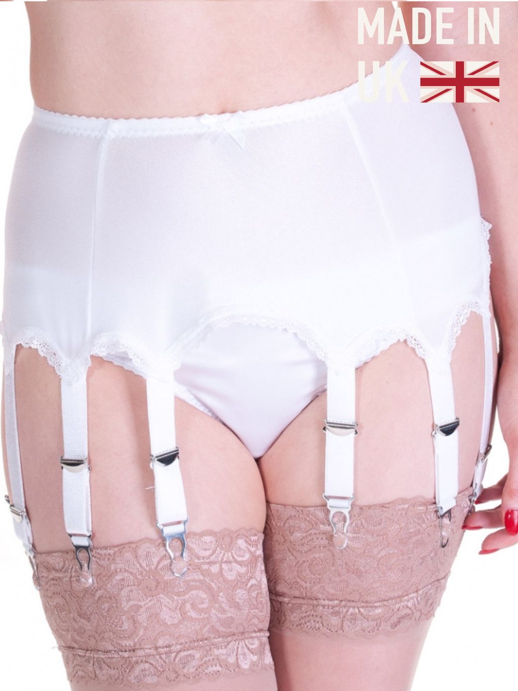 White high-waisted garter belt and panty set with attached white suspenders and lace-up stockings, shown on a model. Features a 'MADE IN UK' graphic overlay in the top right corner.