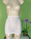 A mdisplay a light pink sheer girdle with a small bow at the waistband and attached garter straps. 