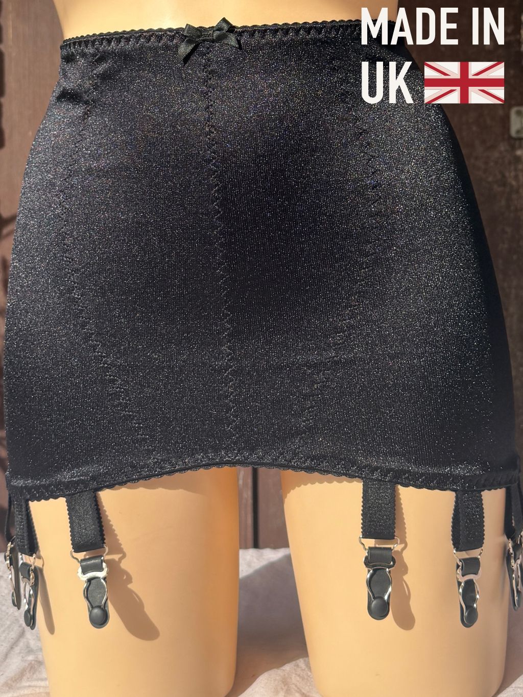 Black girdle with metal clips on a mannequin, featuring a 'MADE IN UK' badge overlay.