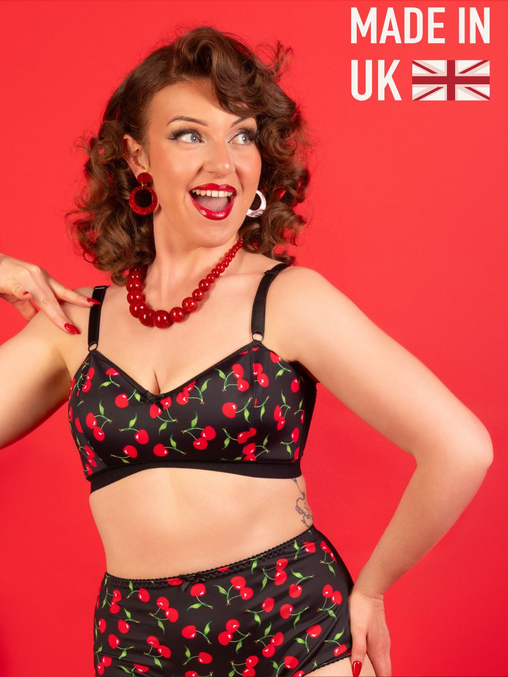 Woman wearing a black  lingerie set  with red cherry pattern on a red background, with 'Made in UK' text.