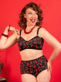 Woman wearing a black lingerie set with red cherry pattern against a red background