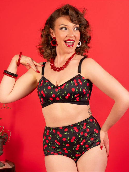 Woman wearing a black lingerie set with red cherry pattern against a red background