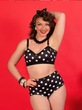 Woman wearing a black polka dot lingerie set against a red background