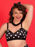 Woman wearing a black polka dot bralette against a red background