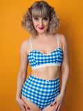 Woman wearing  blue and white checkered lingerie against an orange background