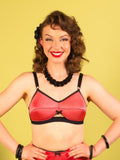 Woman wearing a coral cone bra with black straps against a yellow background