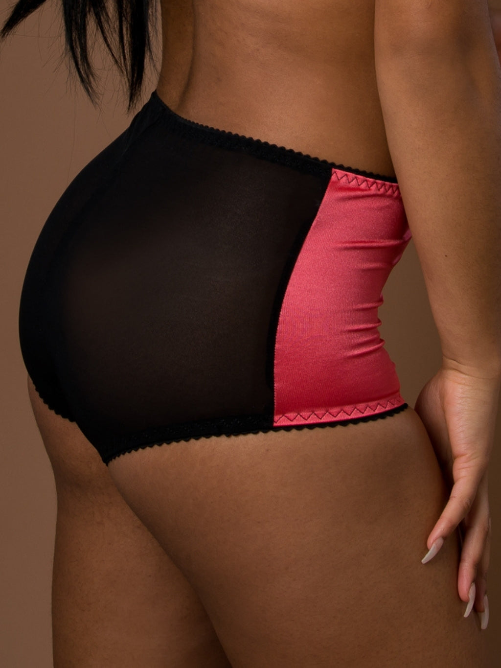 Black and coral retro knickers on a person against a brown background