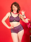 Woman wearing a leopard print lingerie set with a red background