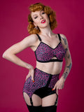 Woman wearing a leopard print lingerie set against a pink background