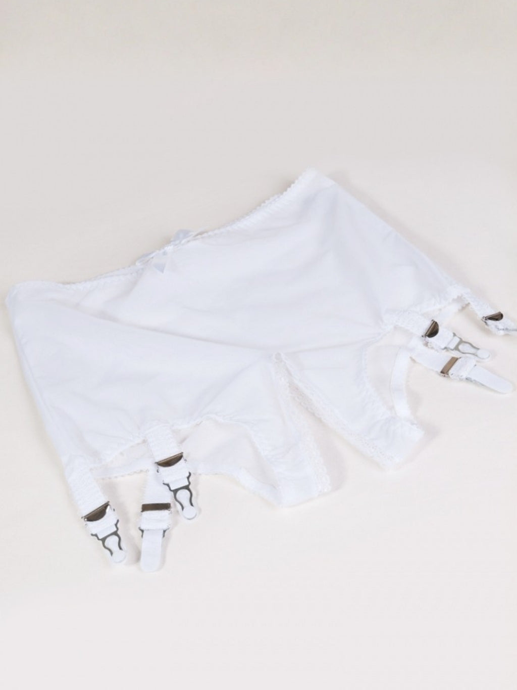 White panty girdle with white suspenders on a beige background