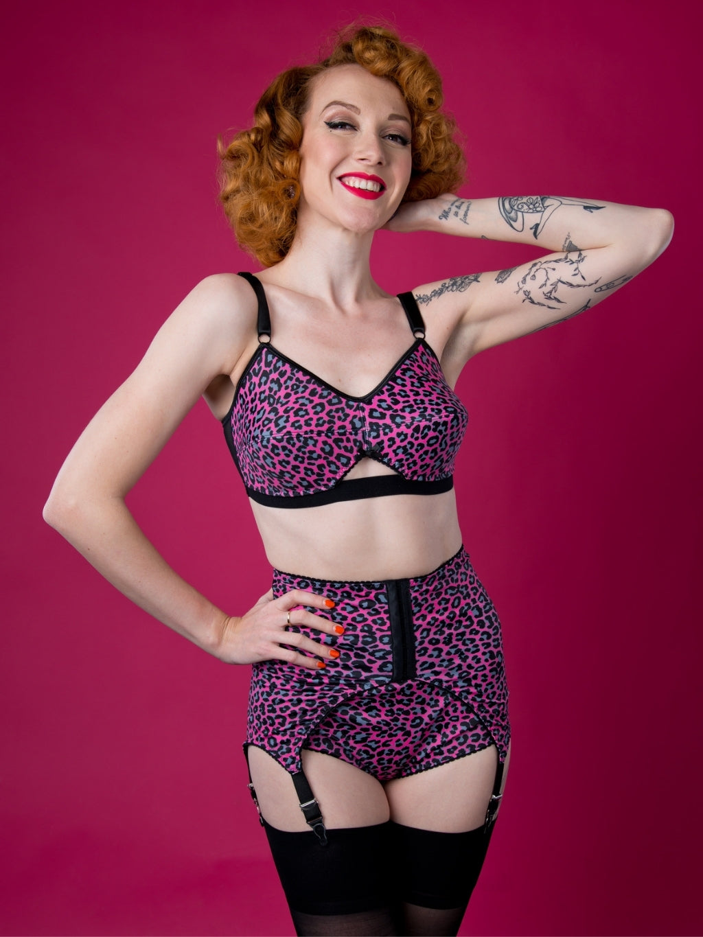 Woman wearing a leopard print lingerie set against a pink background