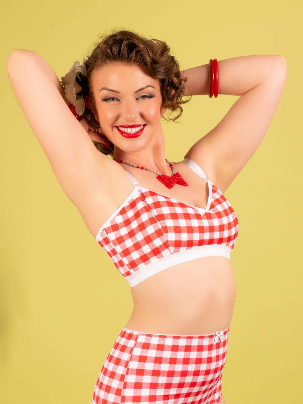 Woman wearing a red and white checkered lingerie set against a yellow background