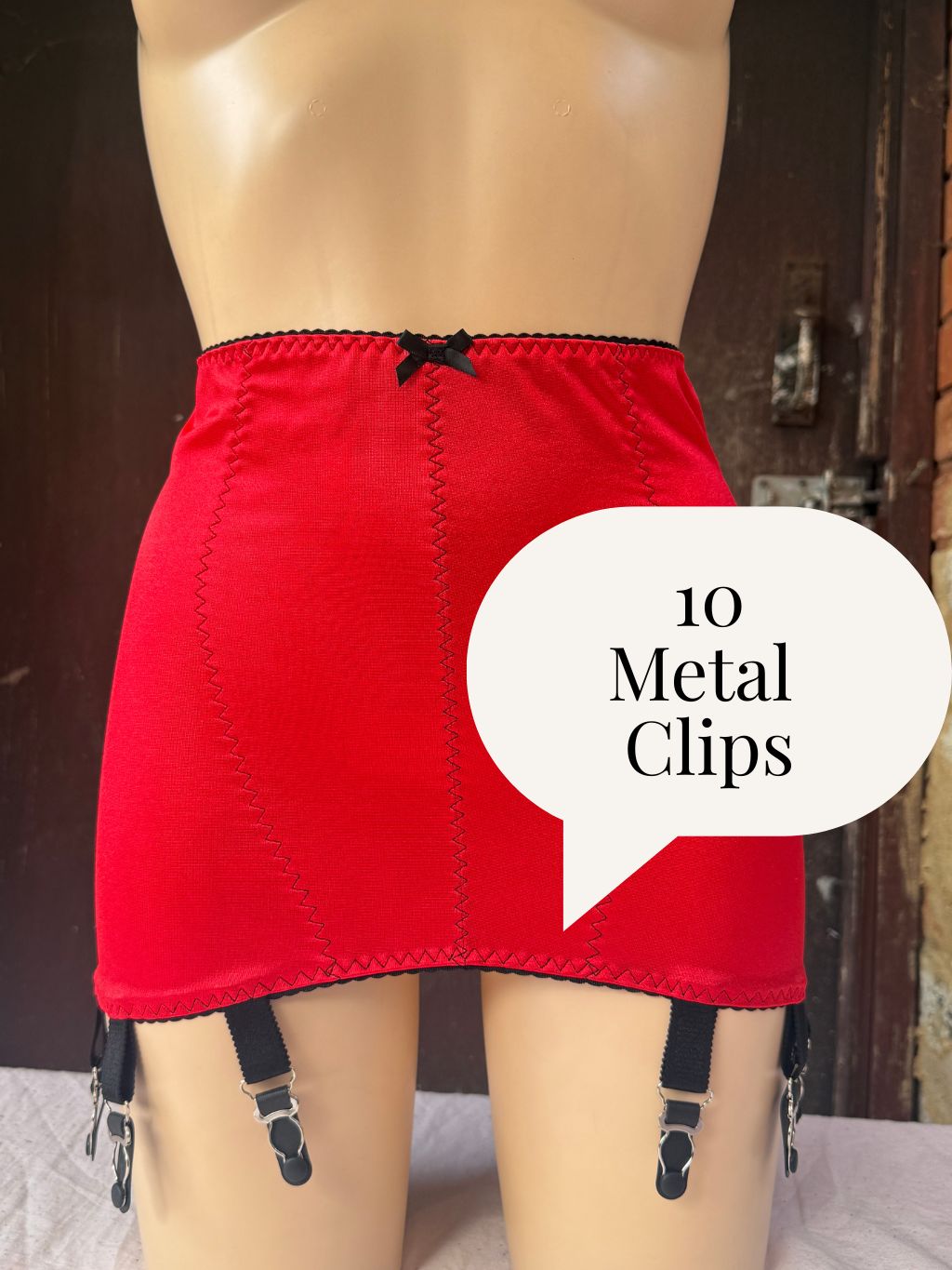 Red girdle with black trim and black metal clips, shown on a mannequin with a speech bubble overlay reading '8 Metal Clips'.