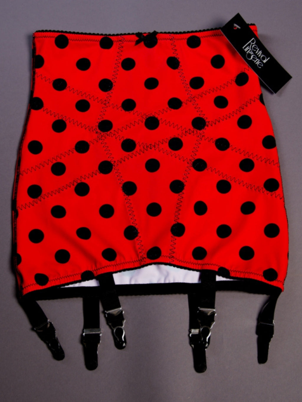 Red Girdle with black polka dots and suspenders on a gray background