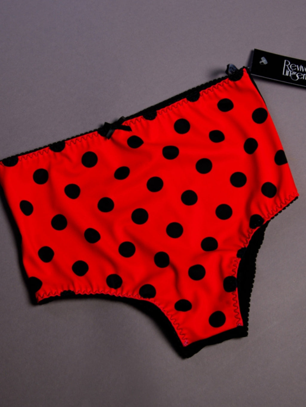 Red underwear with black polka dots on a gray background