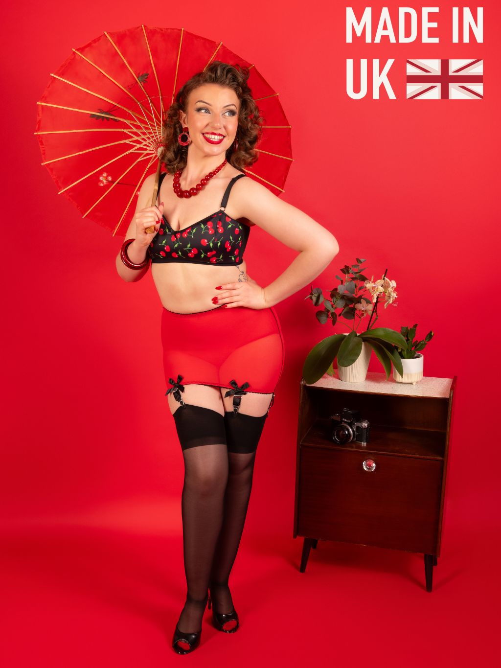 Woman in vintage lingerie holding a red parasol with 'Made in UK' text on a red background