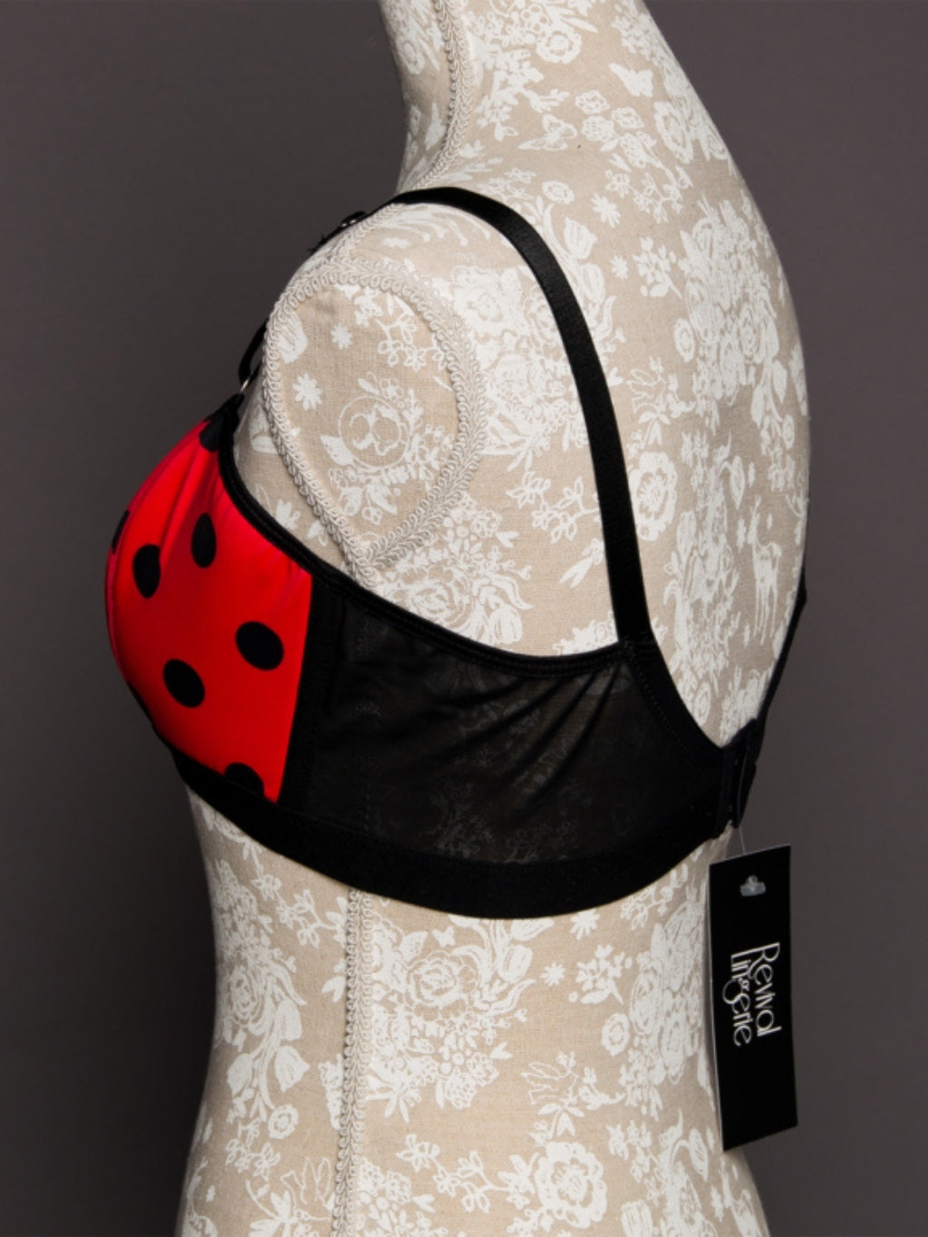 Black bra with red ladybug design on a mannequin against a dark background