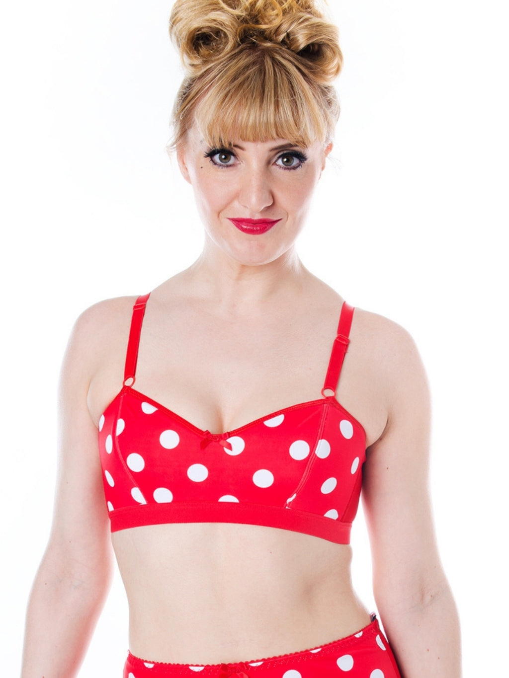 Woman wearing a red polka dot bralette on a white background