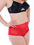 Person wearing a black bra and red high-waisted bottoms sheer on a white background