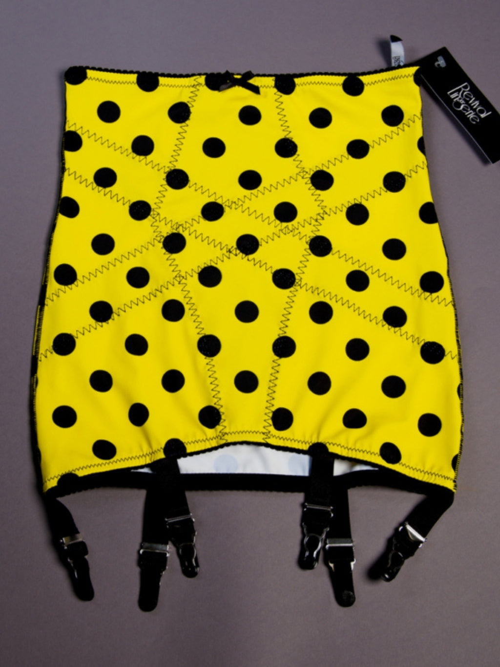 Yellow girdle with black polka dots and straps on a gray background