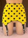 Yellow and black polka dot roll on girdle with attached black garter straps, displayed on a mannequin.