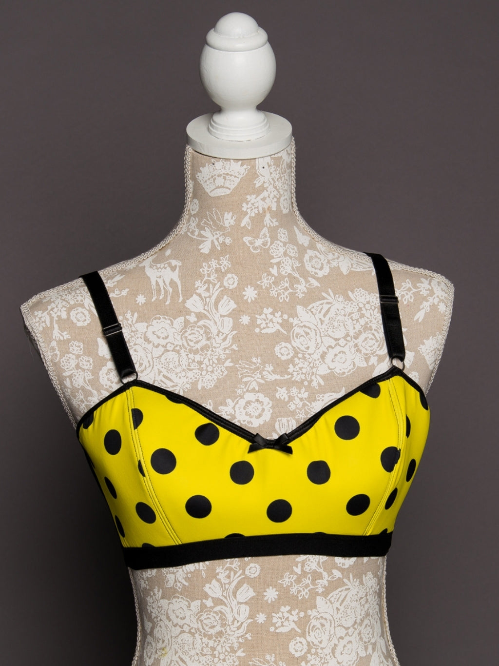 Yellow bra with black polka dots on a mannequin against a lace background